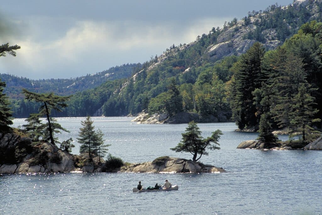 Canoe on the water below the white quartzite hills of Killarney Provincial Park
