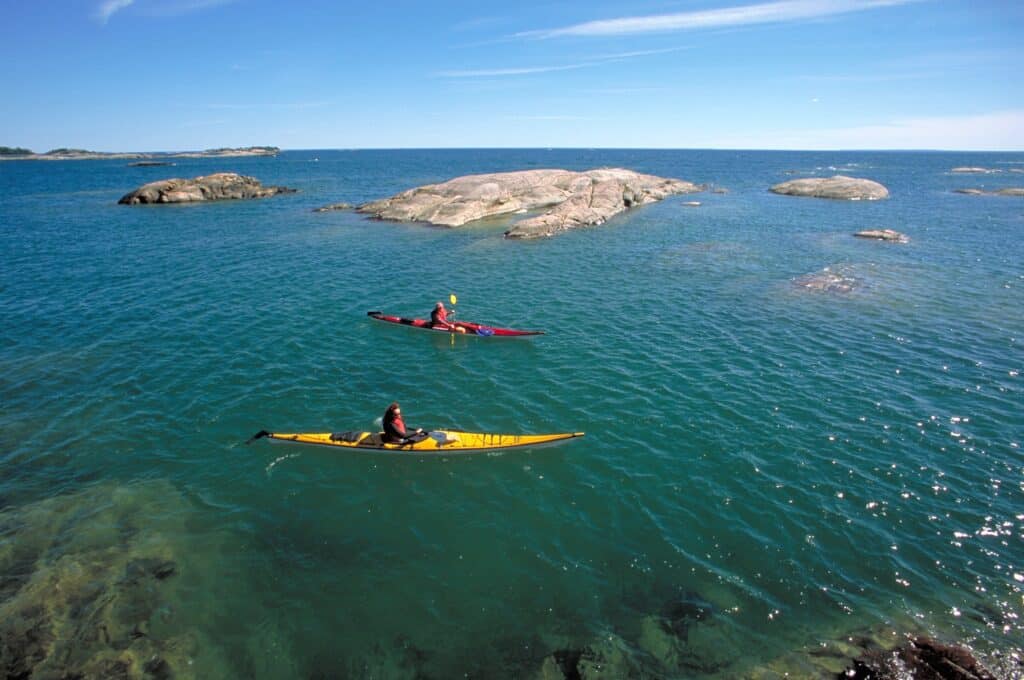 Two sea kayaks on turquoise water among the pink granite islands
