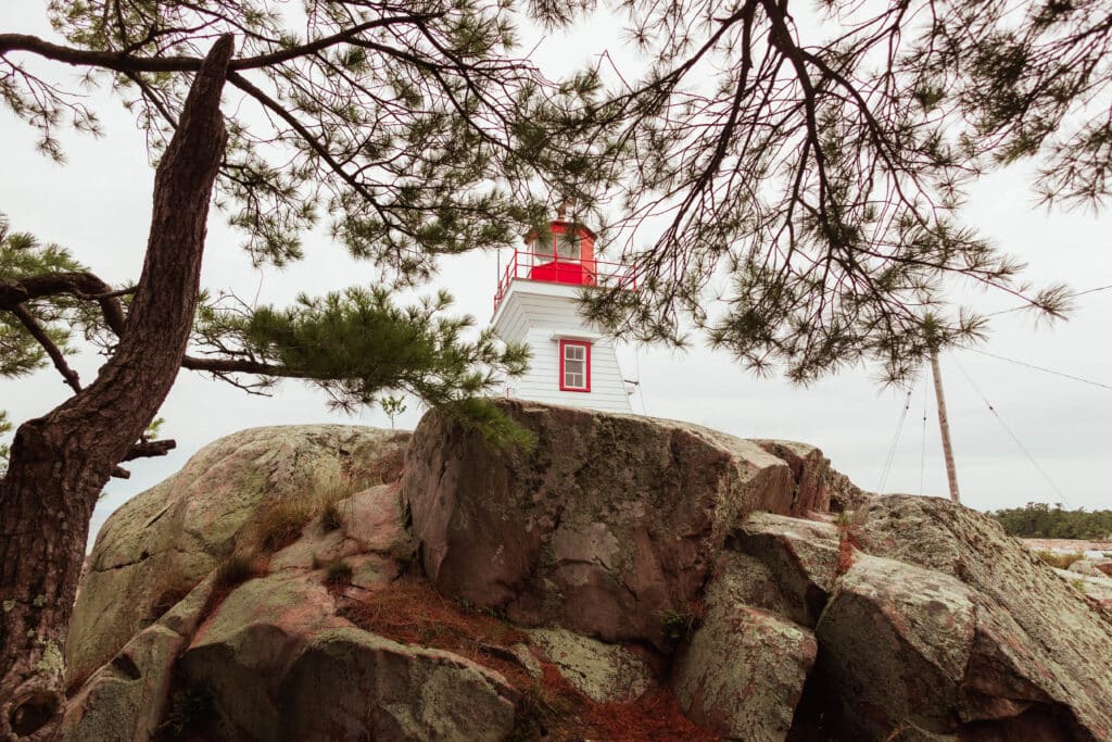 The red-and-white Killarney lighthouse standing on the pink granite point