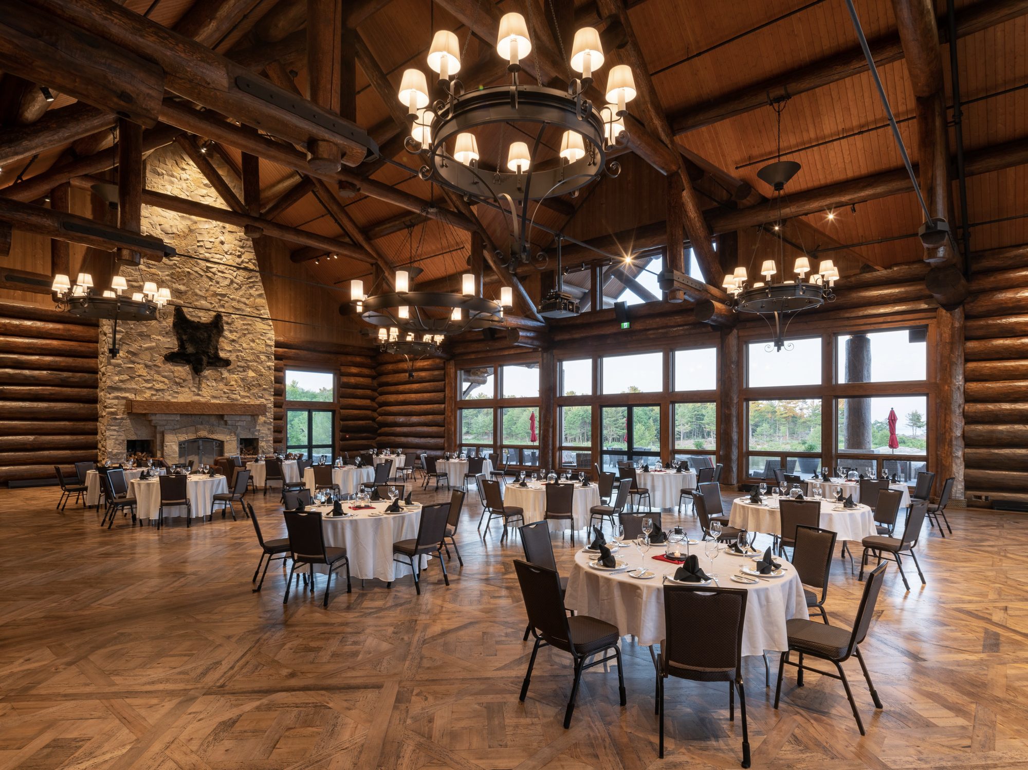 Granite Ridge Hall set for a banquet — log trusses, stone fireplace, glass walls