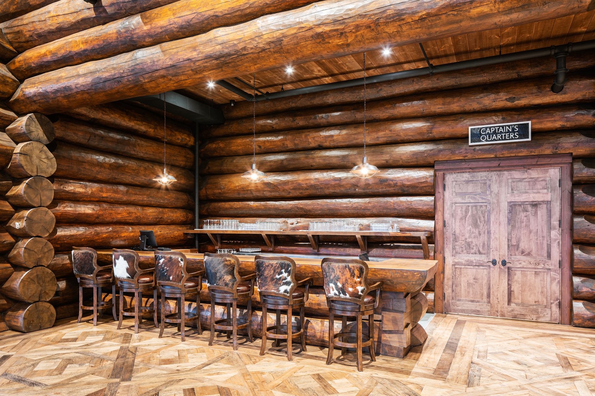 The log bar outside Captain's Quarters — live-edge counter and cowhide stools