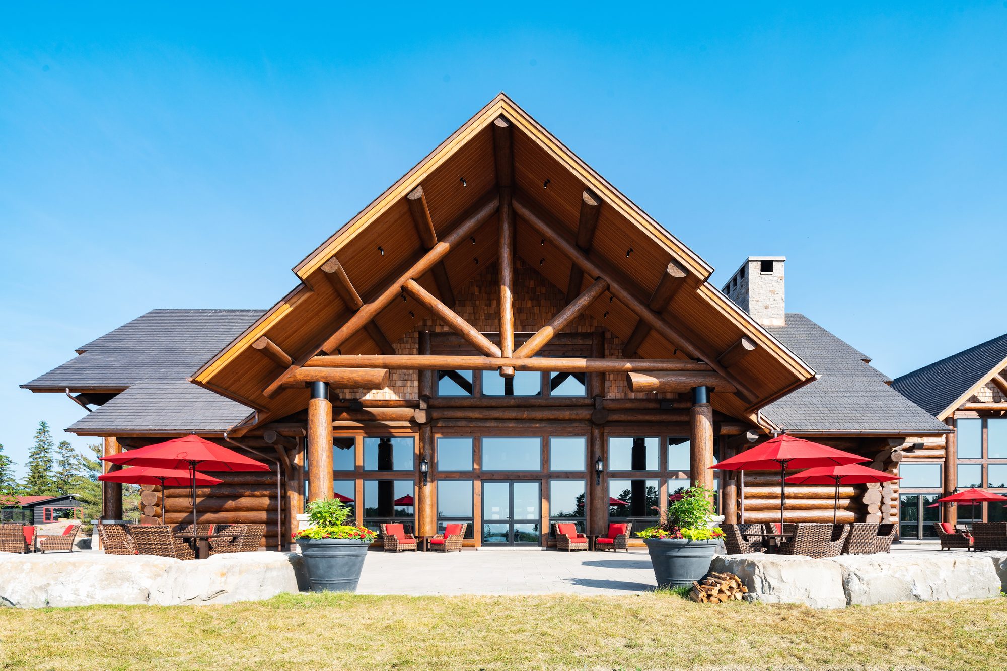 The Granite Ridge Terrace — red umbrellas beneath the great log gable