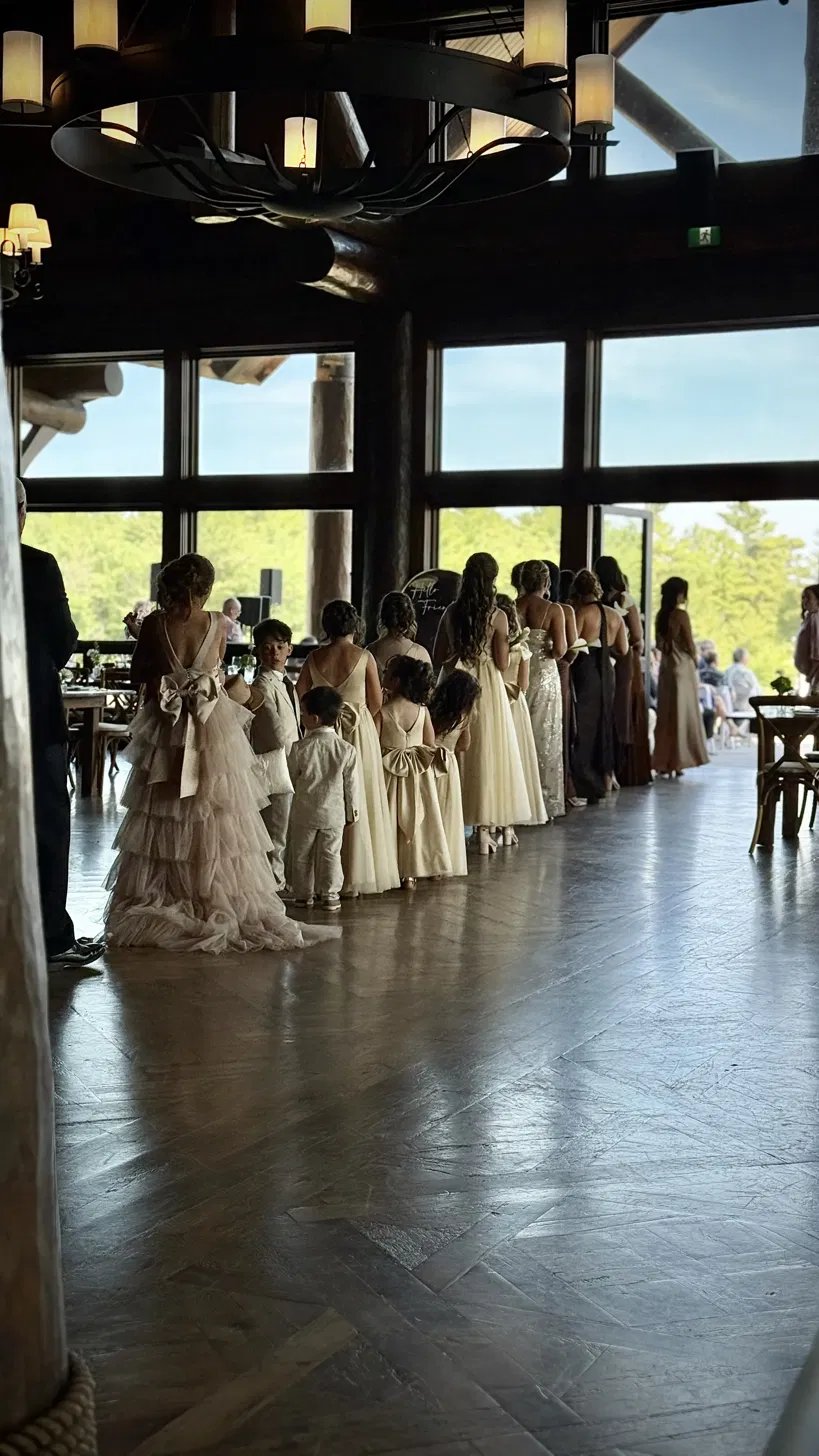 The wedding party filing across the herringbone floor of the hall, forest through the glass