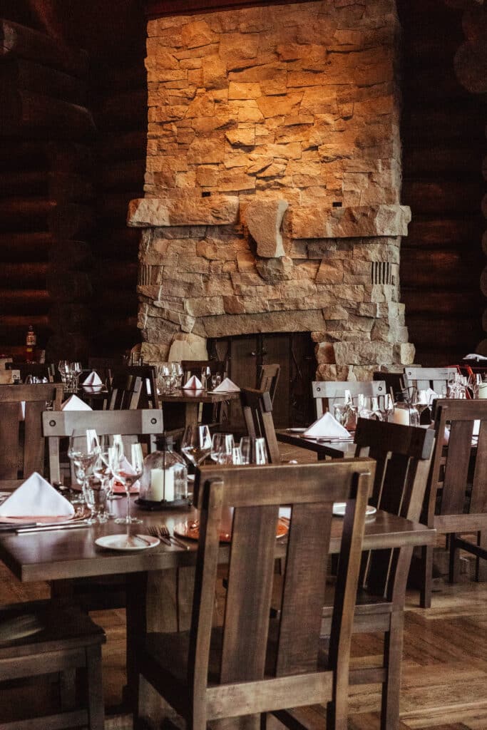 The Ranch House dining room glowing around its dry-stacked stone fireplace