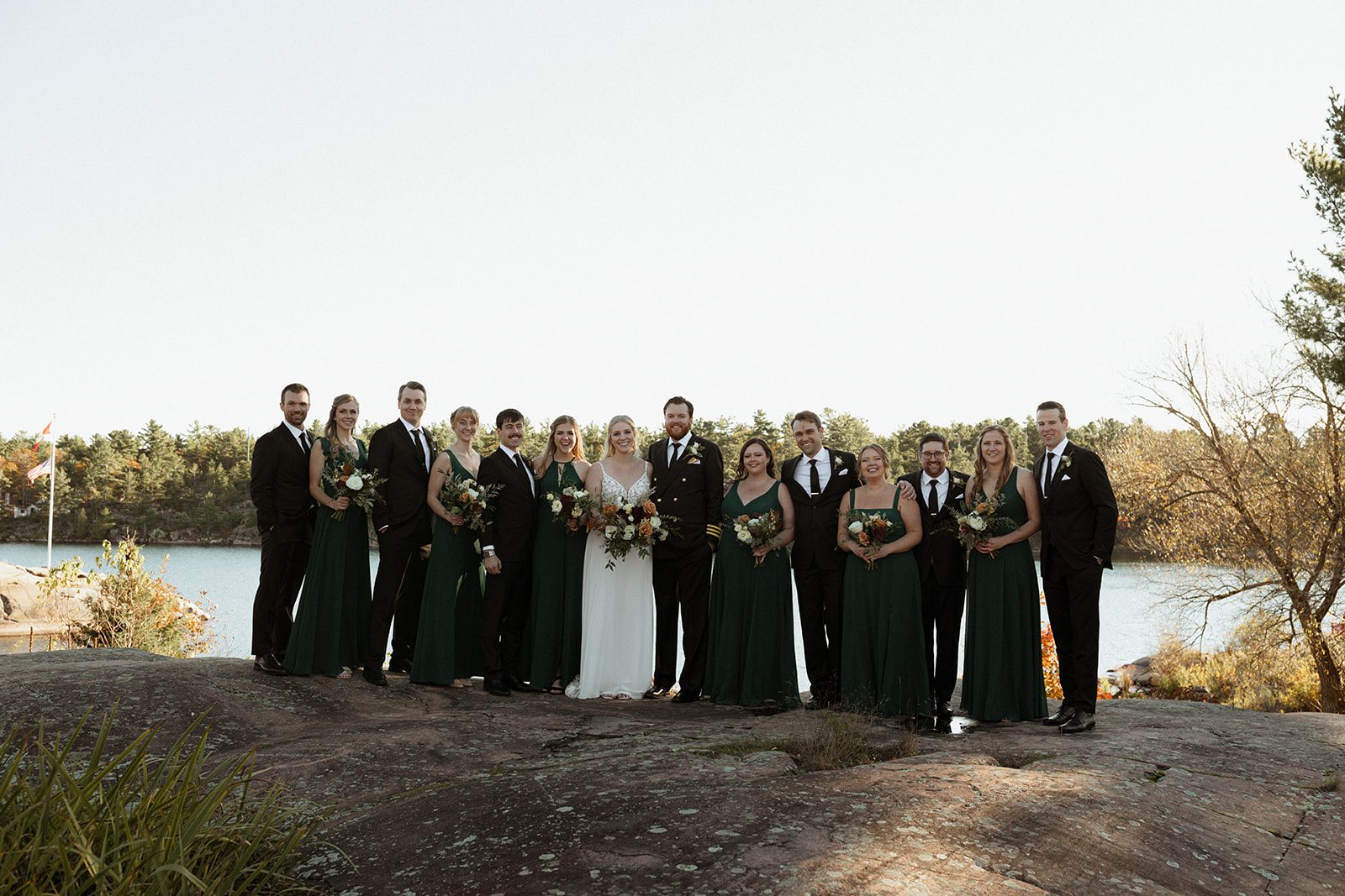 The full wedding party gathered on a granite outcrop above the water