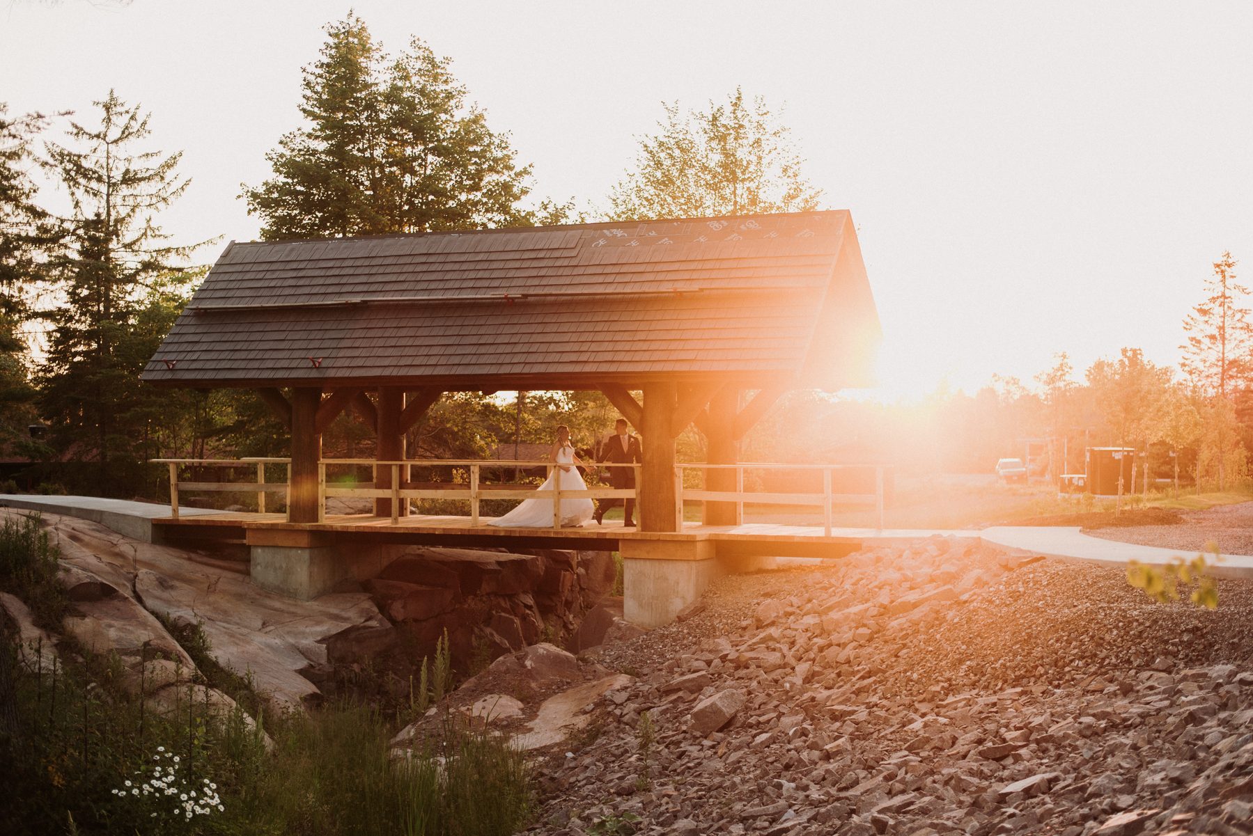 Bride and groom crossing the covered timber bridge in golden light